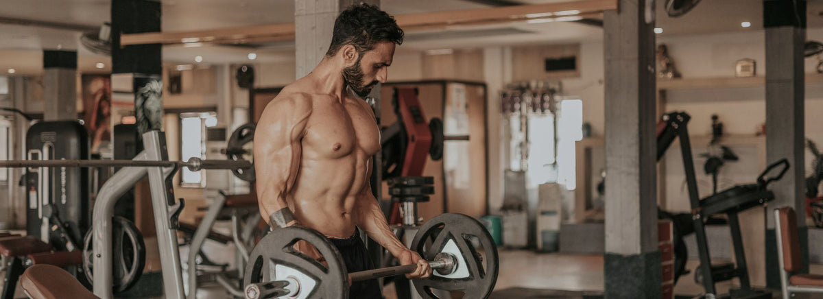 Man lifting a barbell during a strength training workout inside a gym.