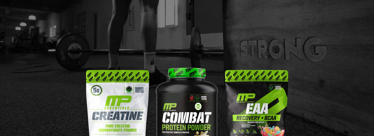 Three MusclePharm supplement tubs including Creatine, Combat Protein, and EAA lined up in a gym.