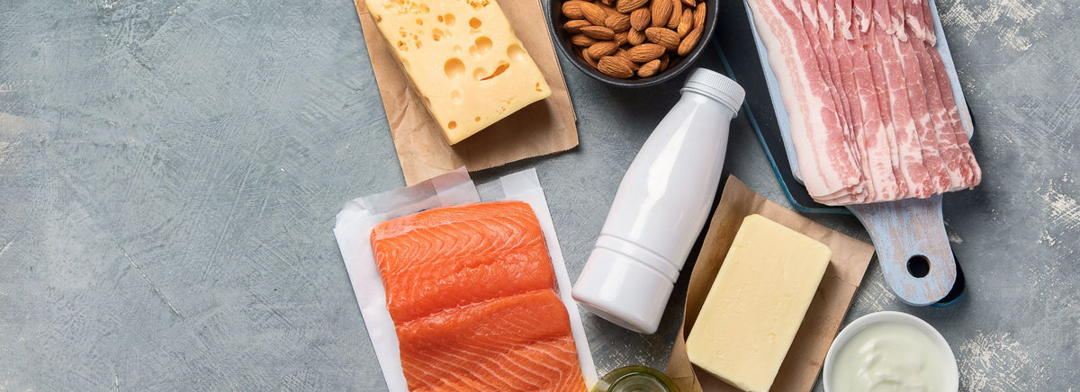 Flat lay of protein and fat sources including salmon, cheese, almonds, bacon, and dairy.