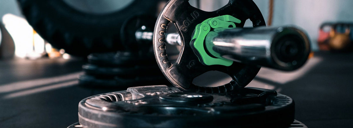 Close-up of a loaded barbell resting on black weight plates on a gym floor.