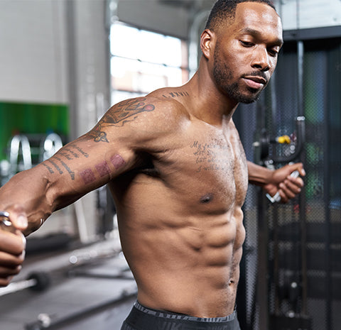 Man performing a cable chest workout in a gym with fitness equipment in the background.